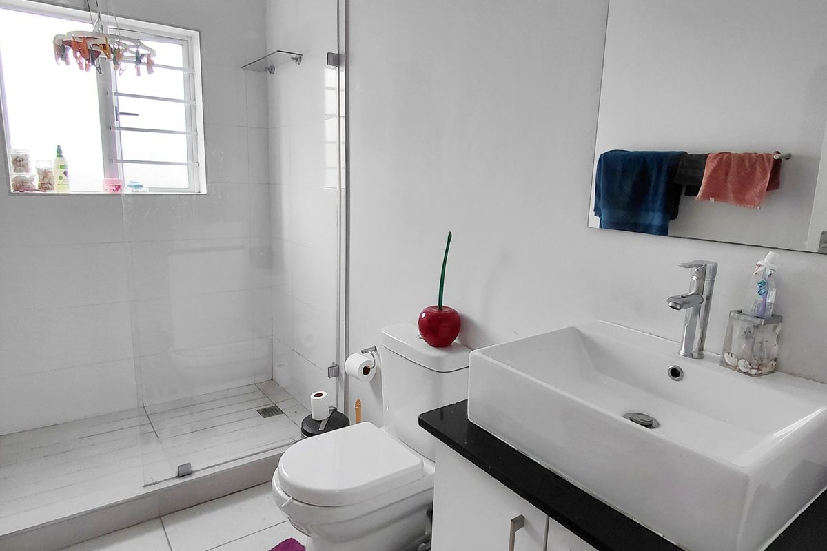 Modern bathroom featuring a glass-enclosed walk-in shower, contemporary countertop basin with vanity storage, and clean tiled finishes.