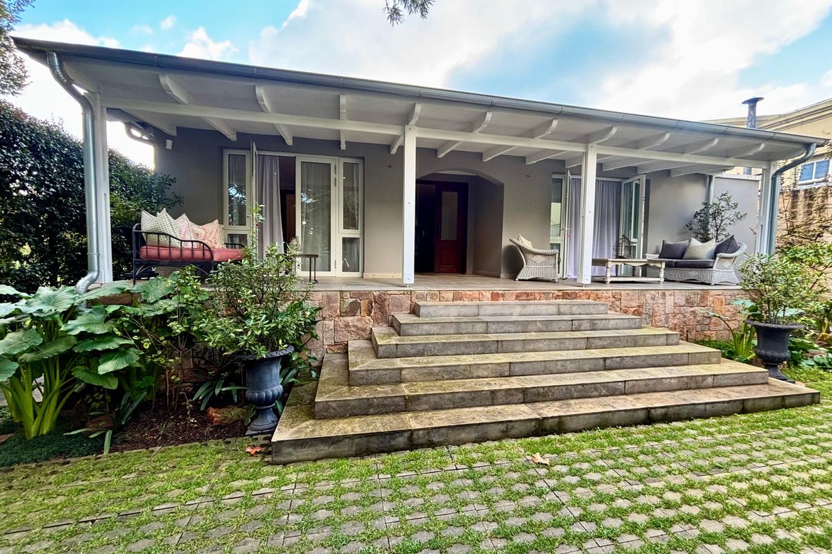 A spacious covered patio featuring stone cladding and wide stone steps, providing a seamless transition between the interior living space and the garden.