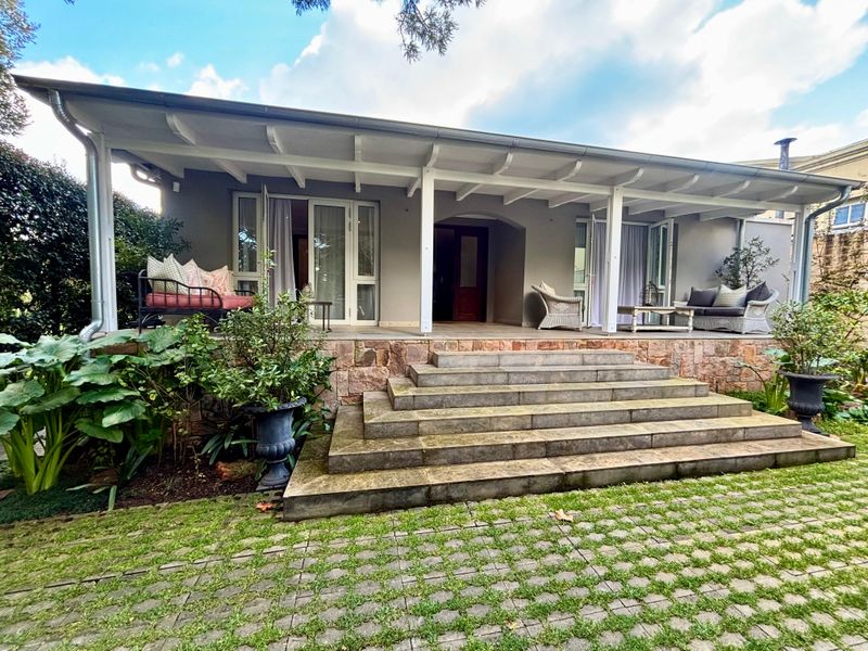 A spacious covered patio featuring stone cladding and wide stone steps, providing a seamless transition between the interior living space and the garden.