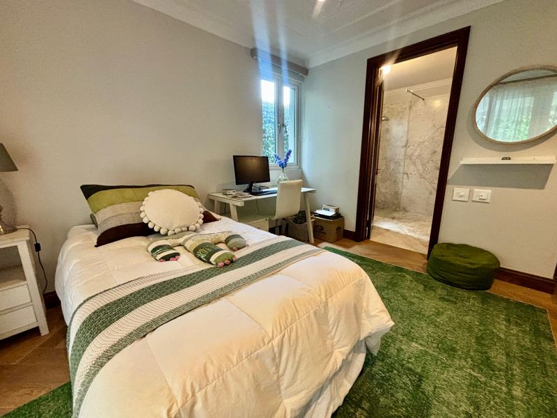 A well-maintained bedroom featuring parquet flooring, coved ceilings, and an adjoining en-suite bathroom with marble wall finishes.