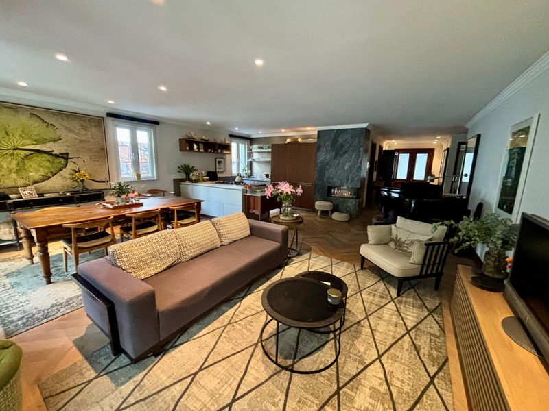 Spacious open-plan living and dining area featuring elegant herringbone timber flooring, a striking stone-clad fireplace, and a modern integrated kitchen.