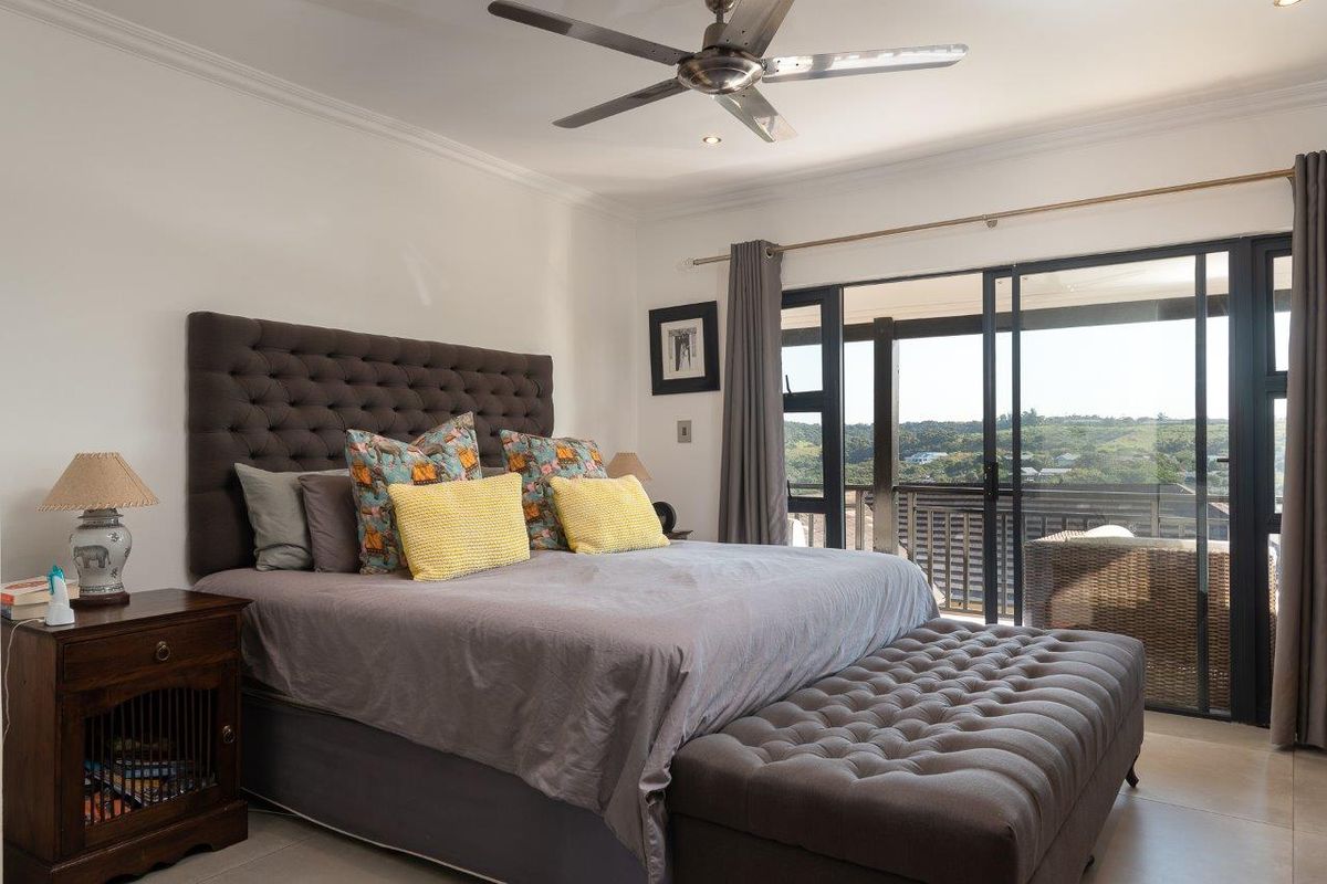 Spacious bedroom featuring tiled floors, a ceiling fan, and large sliding glass doors that open onto a private balcony with scenic views.