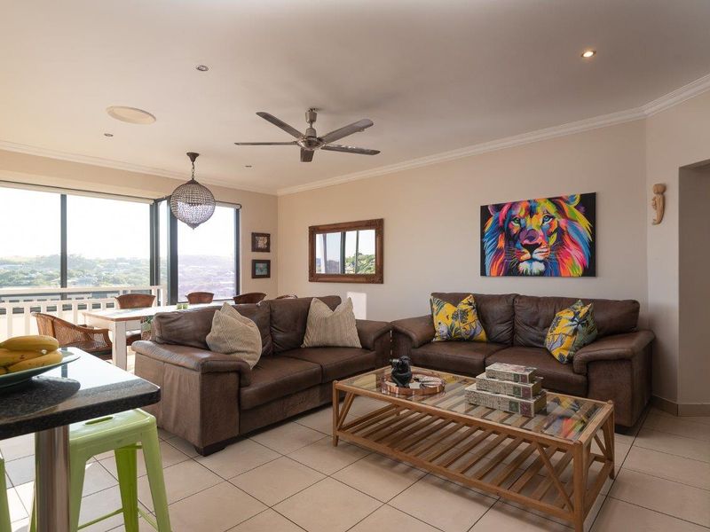 Spacious open-plan living and dining area featuring tiled floors, recessed lighting, a ceiling fan, and large sliding doors leading to an outdoor balcony.