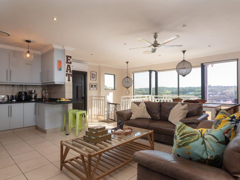 Open-plan living area featuring a modern kitchen with granite countertops, tiled flooring, and large sliding doors offering expansive views.