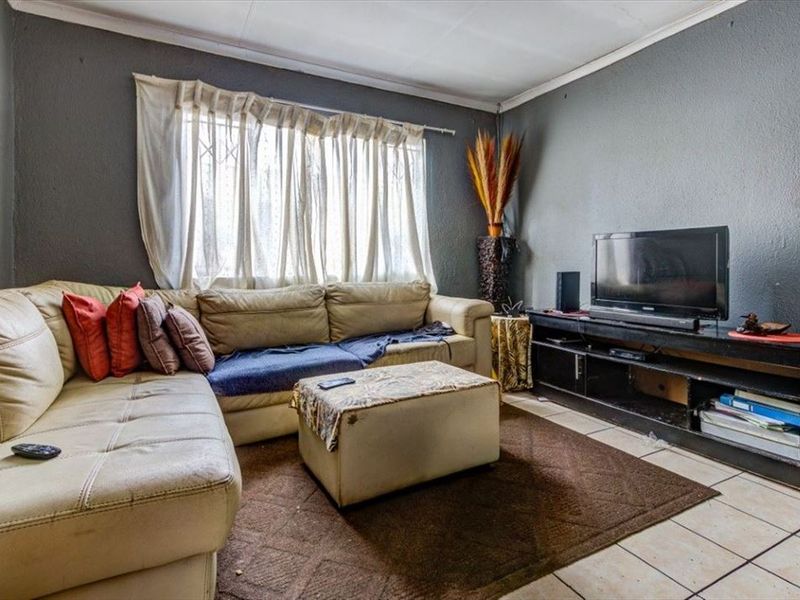 A living room featuring tiled flooring and a window with security bars, finished with dark grey wall paint.