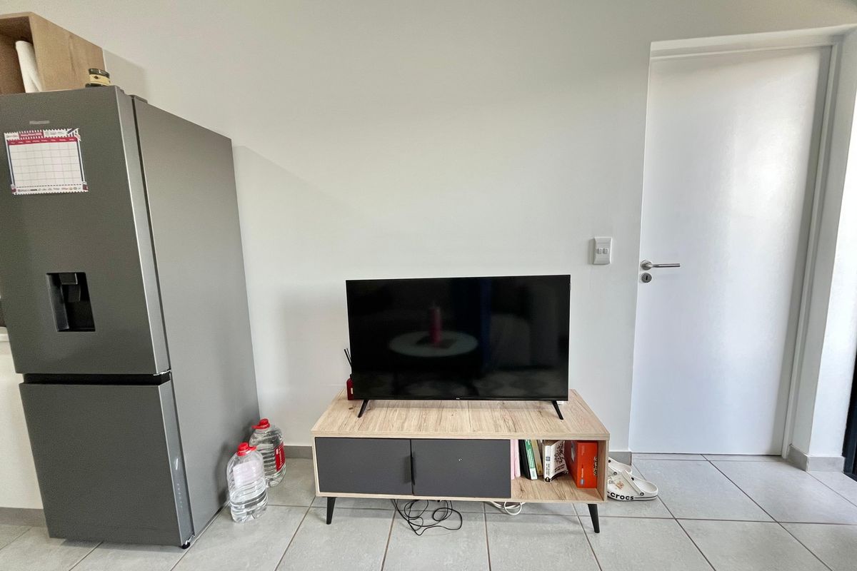 A living area featuring neutral tiled flooring and a standard internal door, providing a functional and clean space.