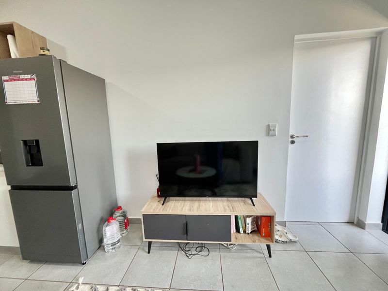 A living area featuring neutral tiled flooring and a standard internal door, providing a functional and clean space.
