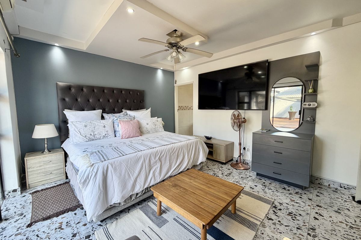 Spacious bedroom featuring a coffered ceiling with recessed lighting, a ceiling fan, and distinctive terrazzo flooring with a built-in vanity unit.