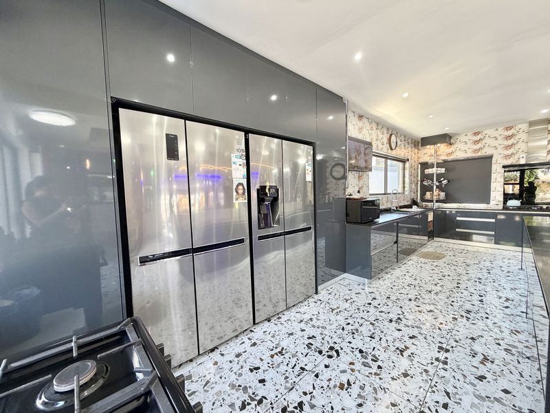 Modern kitchen featuring high-gloss grey cabinetry, terrazzo flooring, and integrated stainless steel appliances with ample storage and workspace.