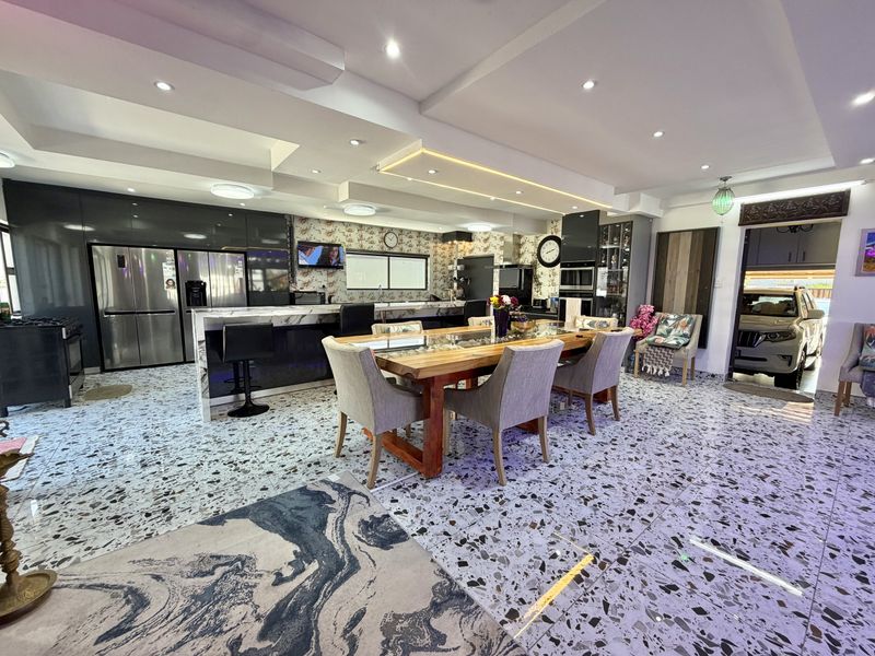 Spacious open-plan kitchen and dining area featuring modern terrazzo flooring, sleek cabinetry, a central kitchen island, and sophisticated recessed ceiling lighting.