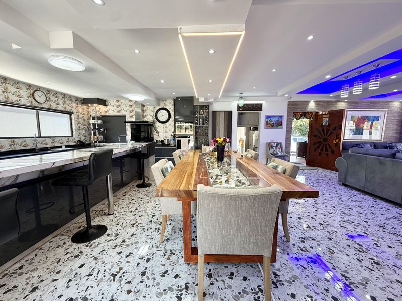 Spacious open-plan living and dining area featuring modern terrazzo flooring, contemporary recessed and cove lighting, and a well-appointed kitchen with integrated appliances.