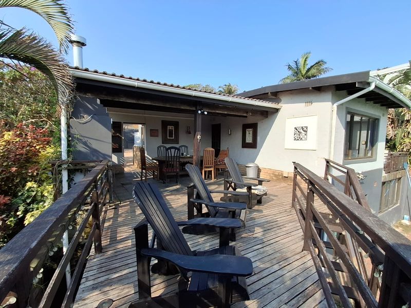 A spacious elevated timber deck patio featuring a covered area, timber balustrades, and direct access to the main house interior.
