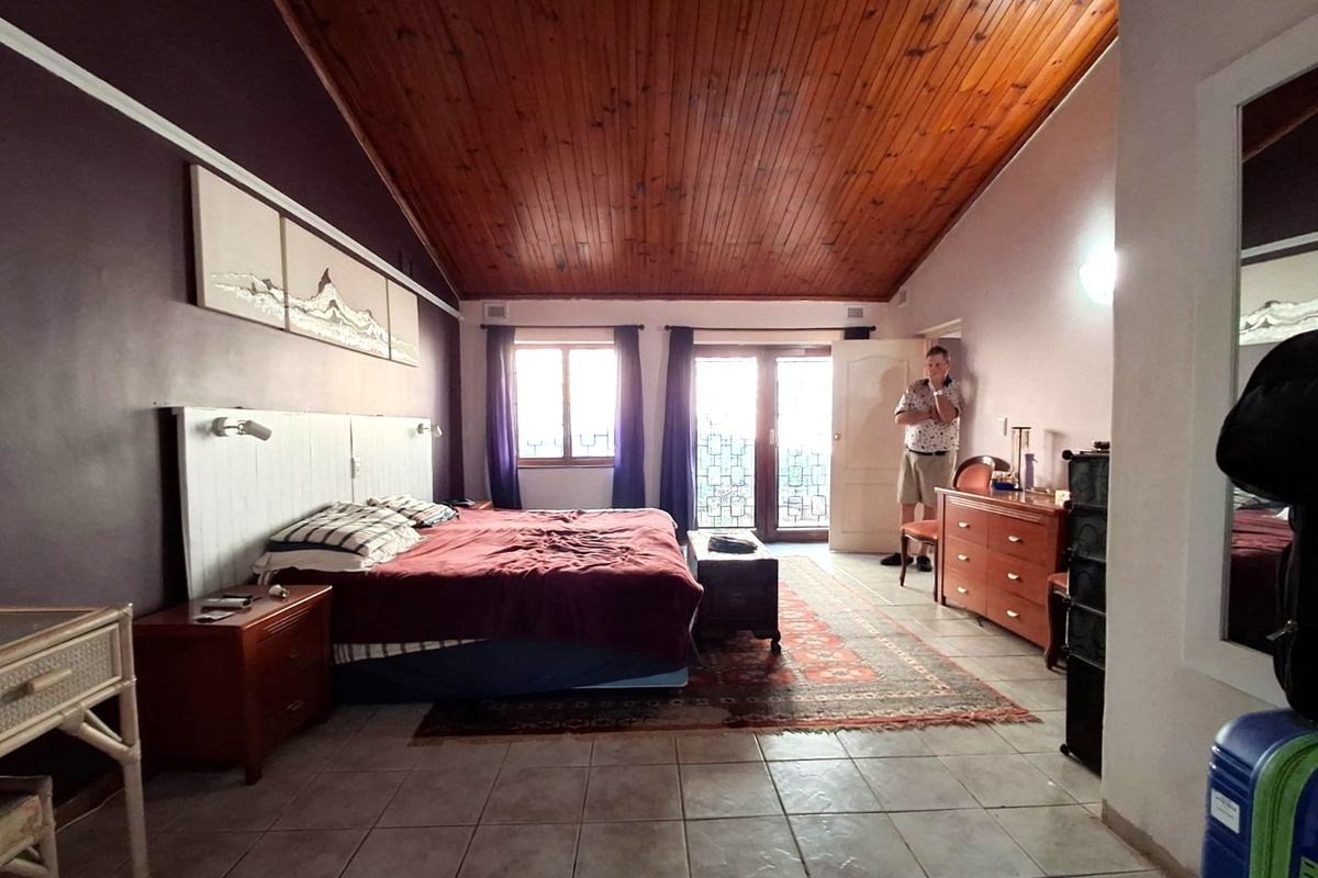 Spacious bedroom featuring a high timber-clad vaulted ceiling, tiled flooring, and direct access to an outdoor area through double glass doors.
