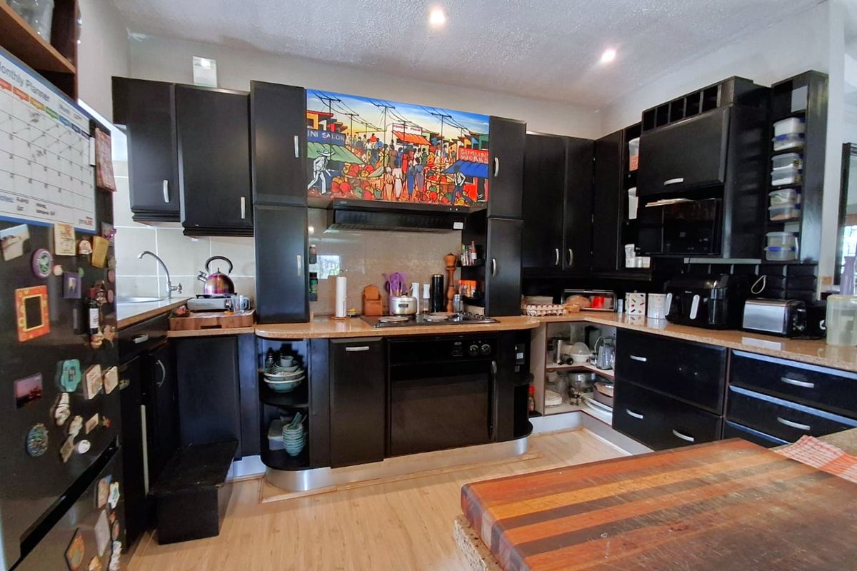 A functional kitchen featuring dark built-in cabinetry, laminate countertops, integrated oven, and gas hob with an overhead extractor fan.