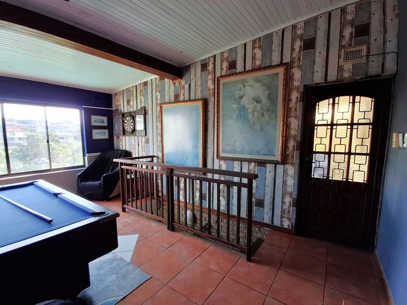 A living area featuring terracotta floor tiles, a timber balustrade, and a decorative leaded glass door with access to an elevated view.