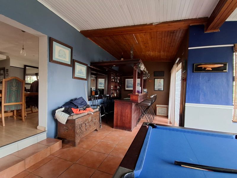 A dedicated bar area featuring a built-in wooden counter, timber ceiling, and tiled flooring, providing a functional space for entertainment.
