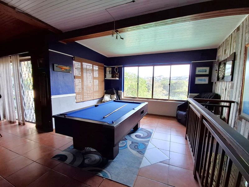 Spacious living area featuring tiled floors, exposed timber beams, and large windows providing natural light and views.