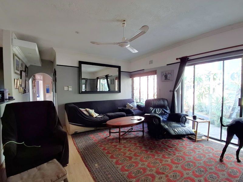 A living room featuring a ceiling fan, coving, and large sliding glass doors that provide access to the outdoor area.