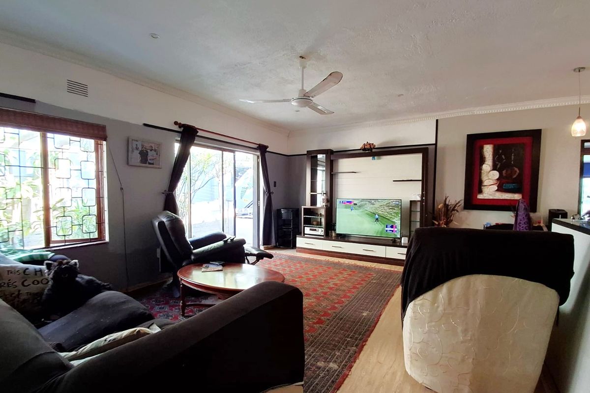 Spacious living room featuring a built-in media unit, ceiling fan, and sliding glass door access to the exterior.