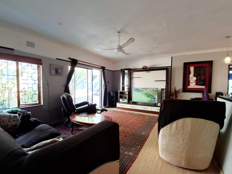 Spacious living room featuring a built-in media unit, ceiling fan, and sliding glass door access to the exterior.