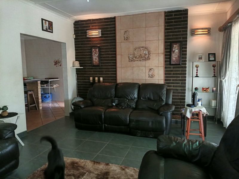 Living room featuring an exposed brick accent wall with decorative tile inlay and tiled flooring, providing a dated but functional living space.