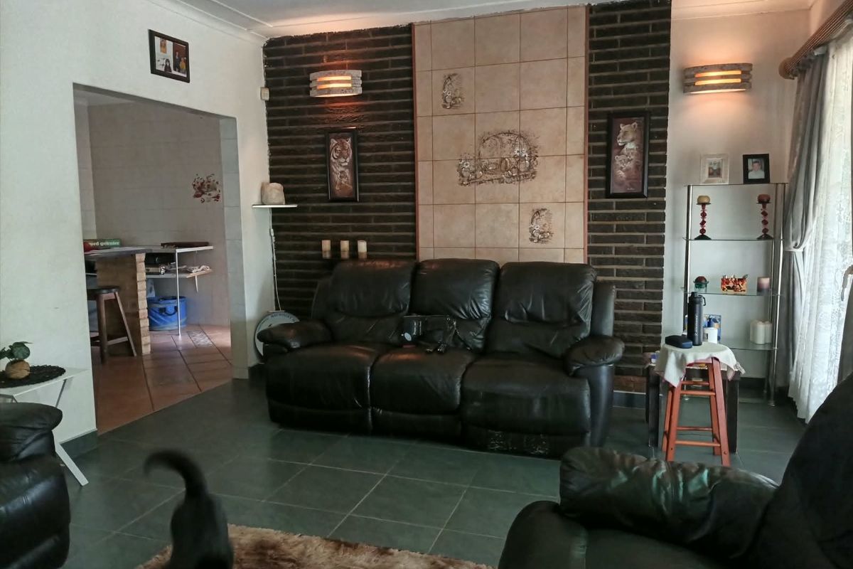 Living room featuring an exposed brick accent wall with decorative tile inlay and tiled flooring, providing a dated but functional living space.