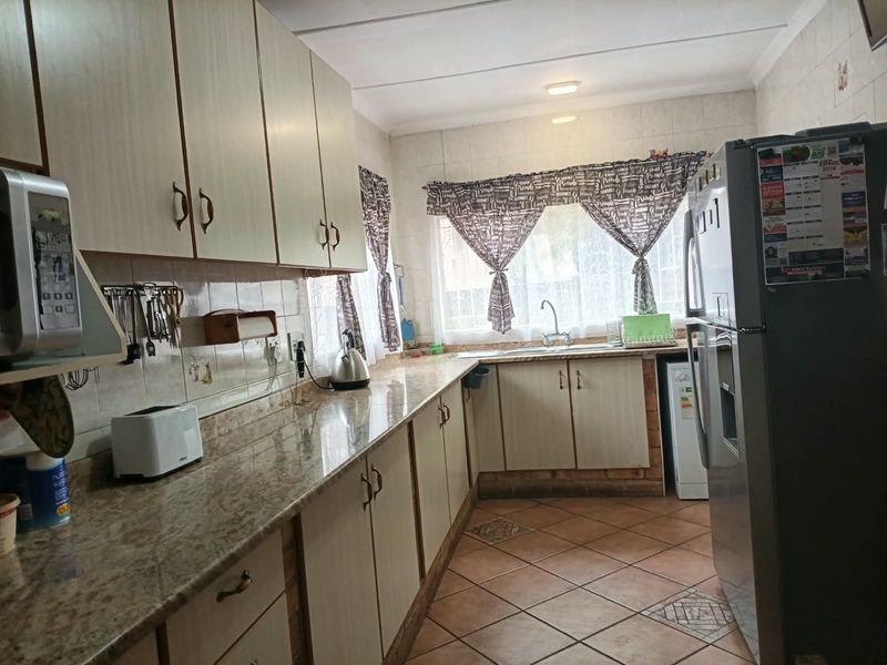A functional kitchen featuring laminate cabinetry, granite countertops, a double basin sink, and tiled flooring, offering a practical layout for daily meal preparation.