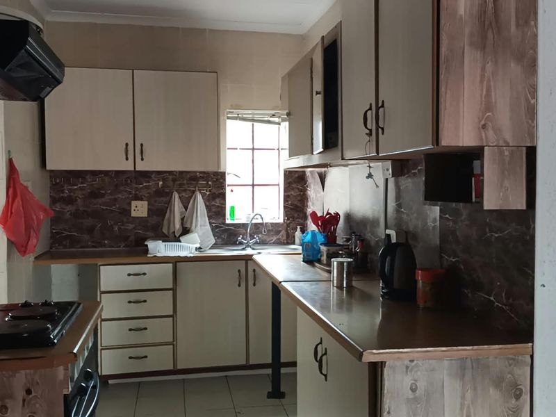 A functional kitchen featuring built-in cabinetry, laminate countertops, a tiled backsplash, and integrated cooking appliances, offering potential for a modern cosmetic update.