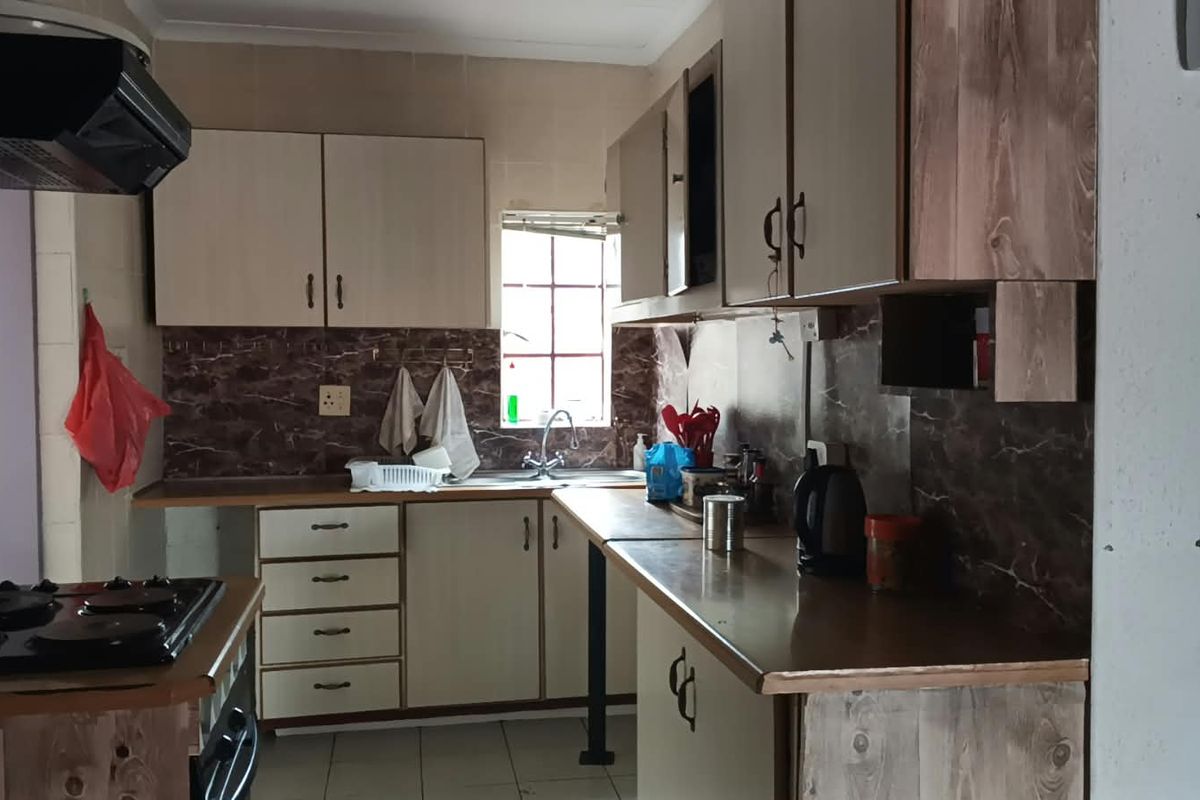A functional kitchen featuring built-in cabinetry, laminate countertops, a tiled backsplash, and integrated cooking appliances, offering potential for a modern cosmetic update.