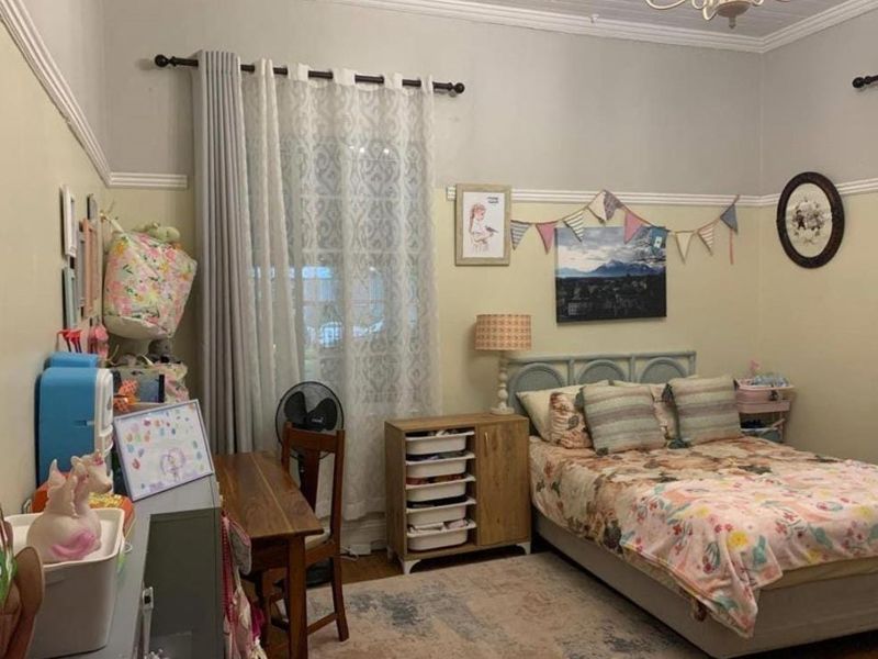 A bedroom featuring classic architectural details including a picture rail and decorative cornice, with timber flooring throughout.