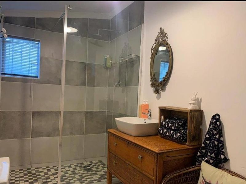 A modern bathroom featuring a spacious walk-in shower with grey tiled walls, a glass screen, and a contemporary vessel sink vanity.