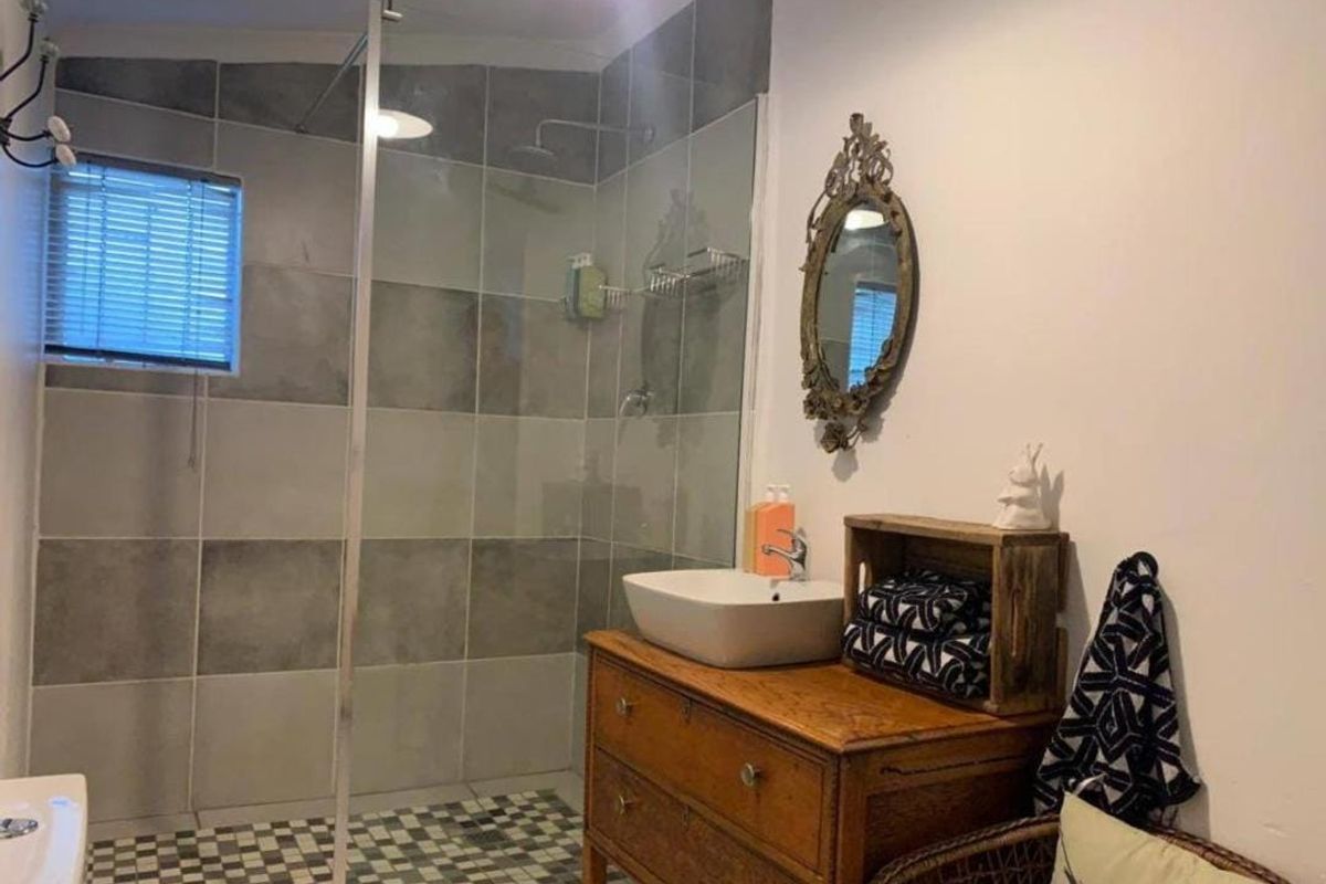 A modern bathroom featuring a spacious walk-in shower with grey tiled walls, a glass screen, and a contemporary vessel sink vanity.