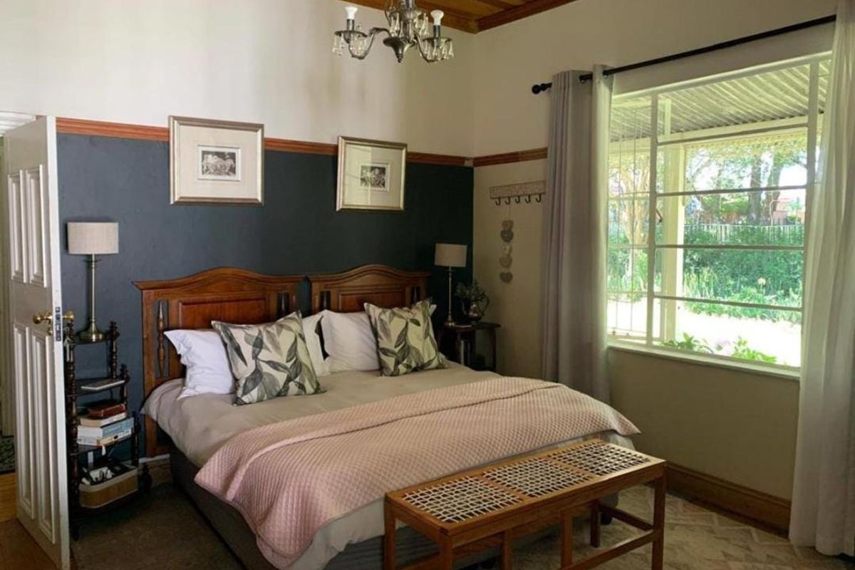 A well-maintained bedroom featuring a timber ceiling, picture rails, and a large window providing natural light and garden views.