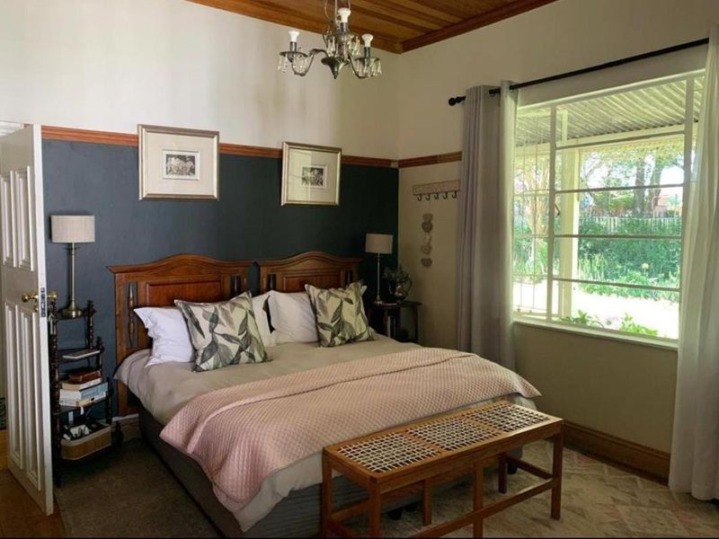 A well-maintained bedroom featuring a timber ceiling, picture rails, and a large window providing natural light and garden views.
