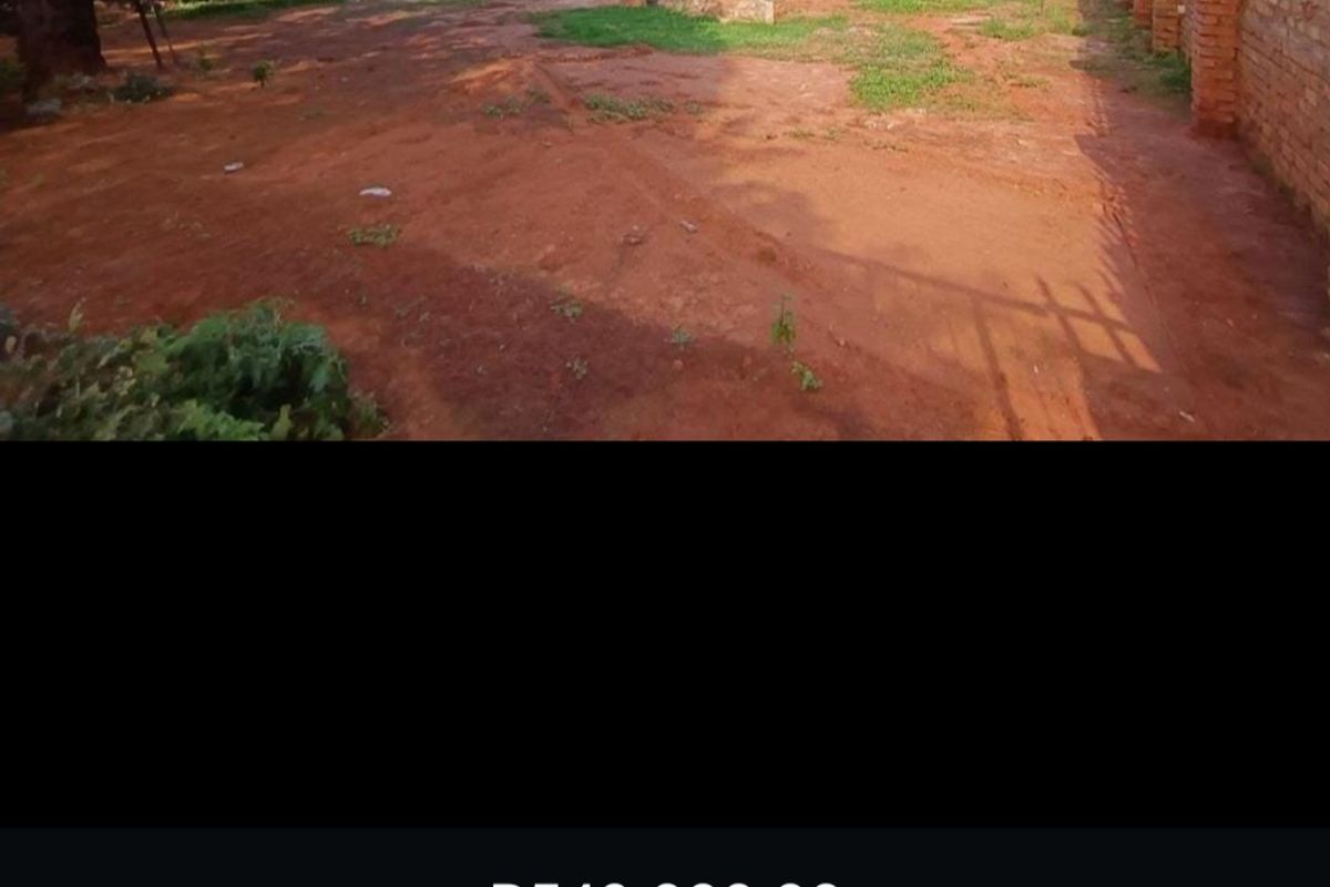 A vacant residential plot featuring a brick perimeter wall and open ground, offering a blank canvas for future development.