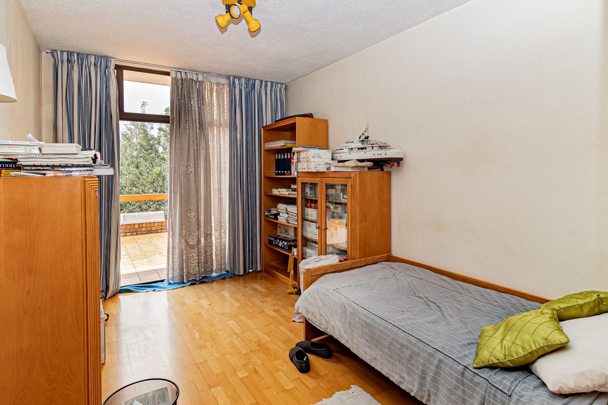 A bedroom featuring laminate flooring and a sliding glass door providing access to an outdoor balcony area.