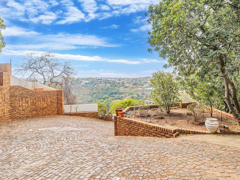 A spacious brick-paved driveway featuring tiered brick retaining walls and elevated views over the surrounding landscape.