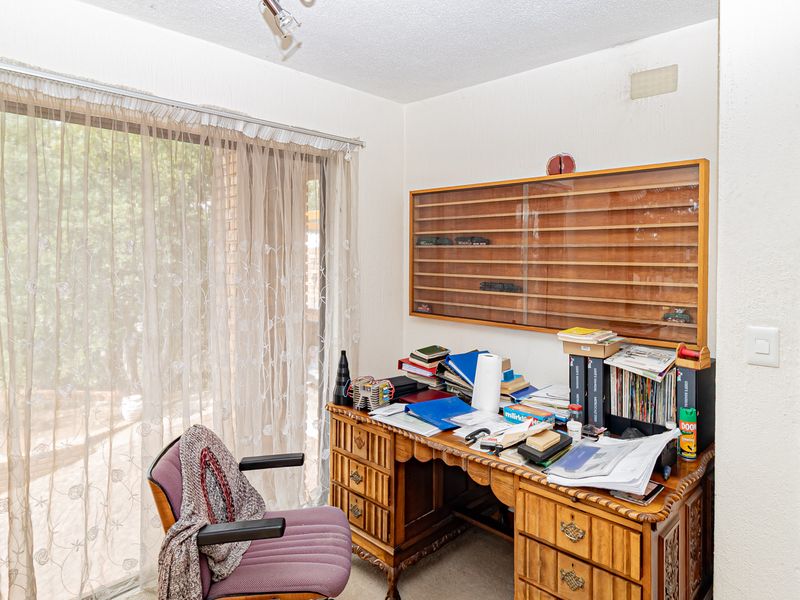 A functional office space featuring a large sliding glass door providing natural light and a wall-mounted display cabinet.
