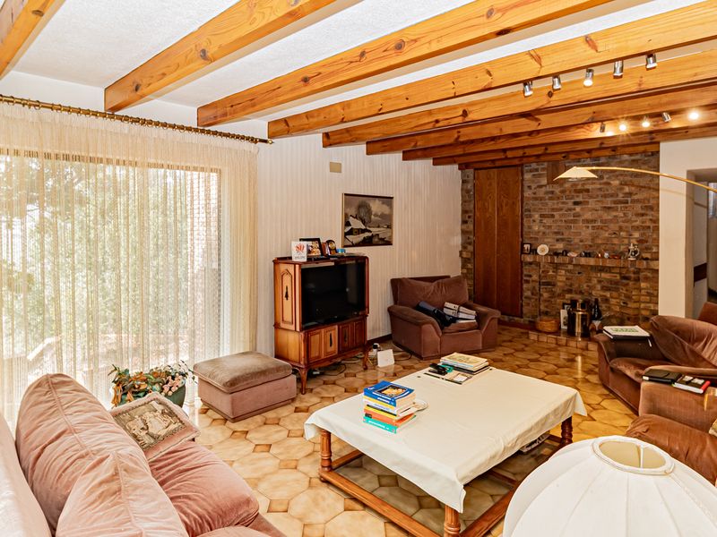 Spacious living room featuring exposed timber ceiling beams, a brick fireplace, and large sliding glass doors providing natural light.