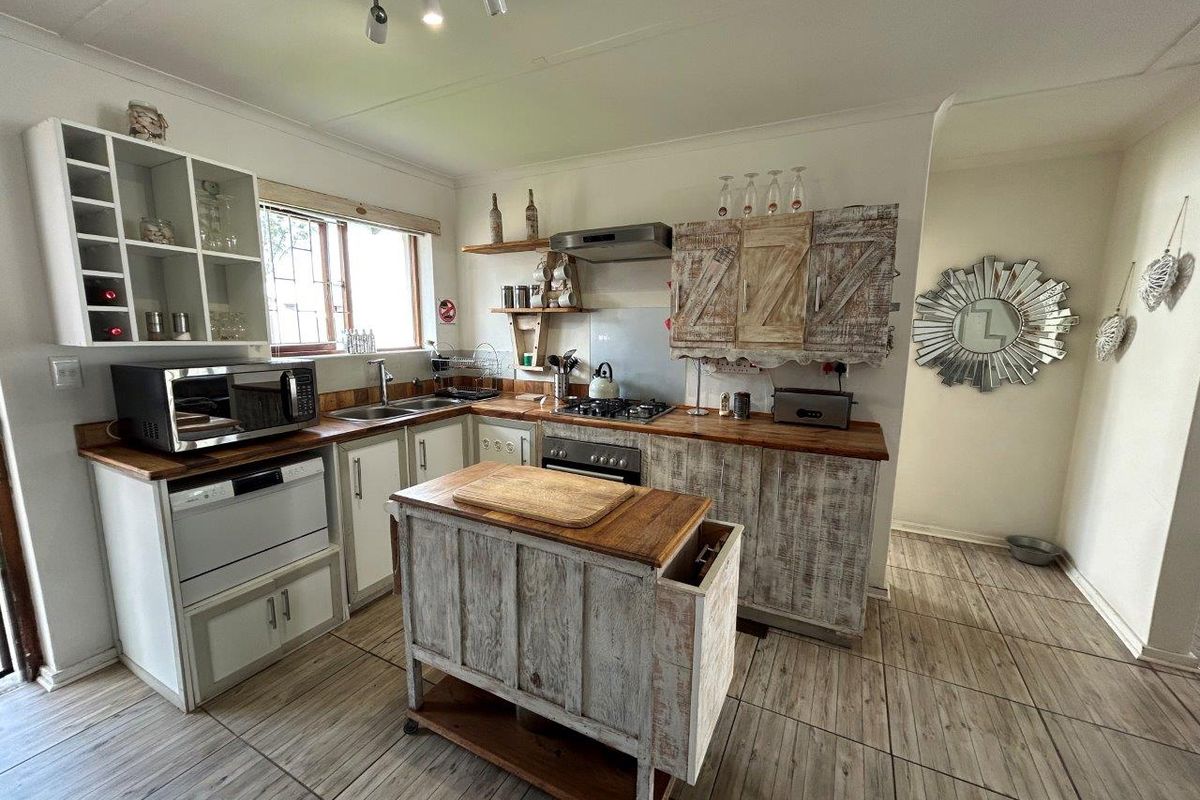 A rustic-style kitchen featuring wooden countertops, built-in oven, gas hob, and custom cabinetry with open shelving and tiled flooring.