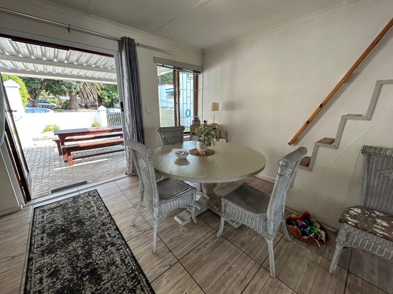 Dining area featuring tiled flooring and direct access to a covered patio through a sliding glass door, with an adjacent staircase.