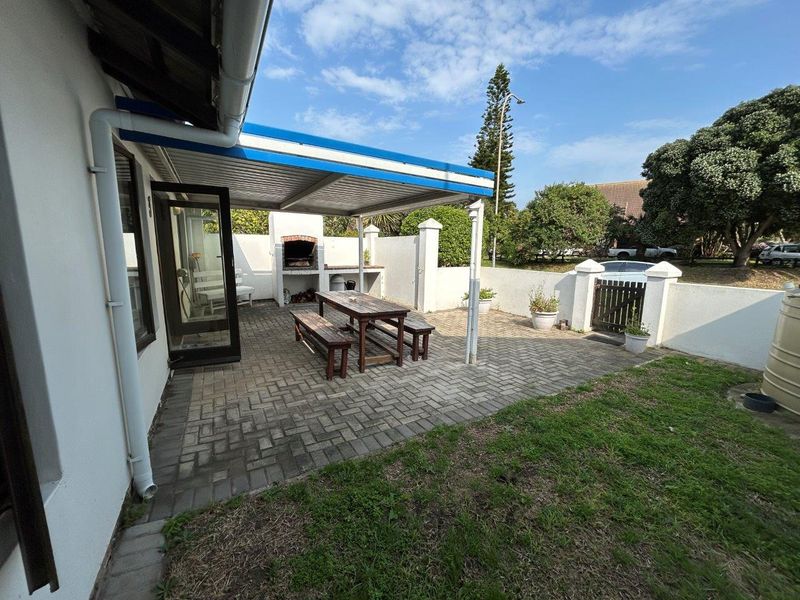 Outdoor patio area featuring a paved floor, covered pergola, and a built-in braai, providing a functional space for outdoor entertaining.