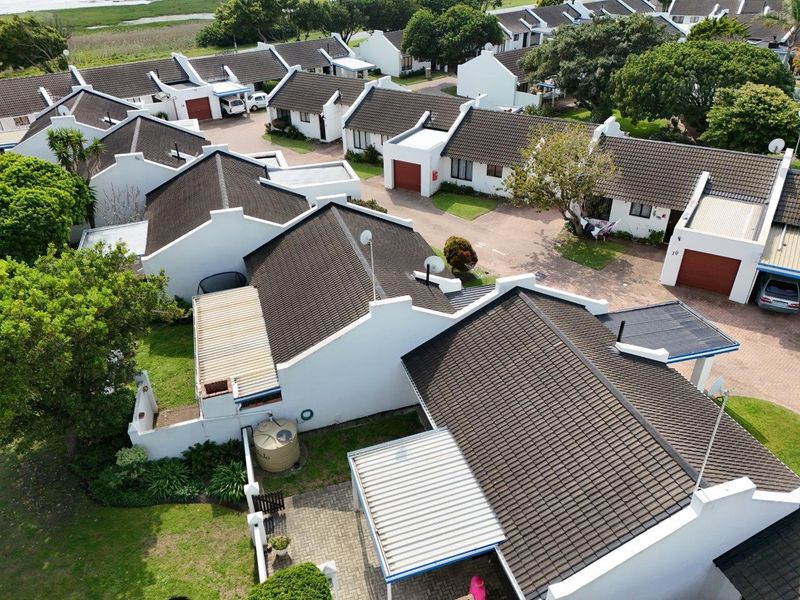 Aerial view of a residential townhouse complex featuring multiple units with tiled roofs, paved driveways, and private garden spaces.