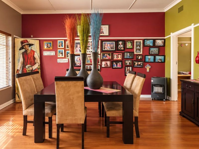 A well-maintained dining room featuring polished timber flooring, classic picture rails, and large windows with venetian blinds, offering a warm and inviting atmosphere.