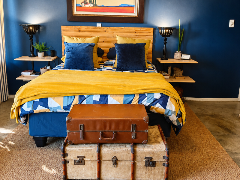 A well-maintained bedroom featuring polished concrete floors, a bold navy accent wall, and custom built-in bedside shelving units.