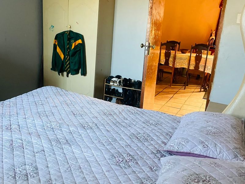 A bedroom interior featuring a view through a doorway into an adjacent dining area with tiled flooring.