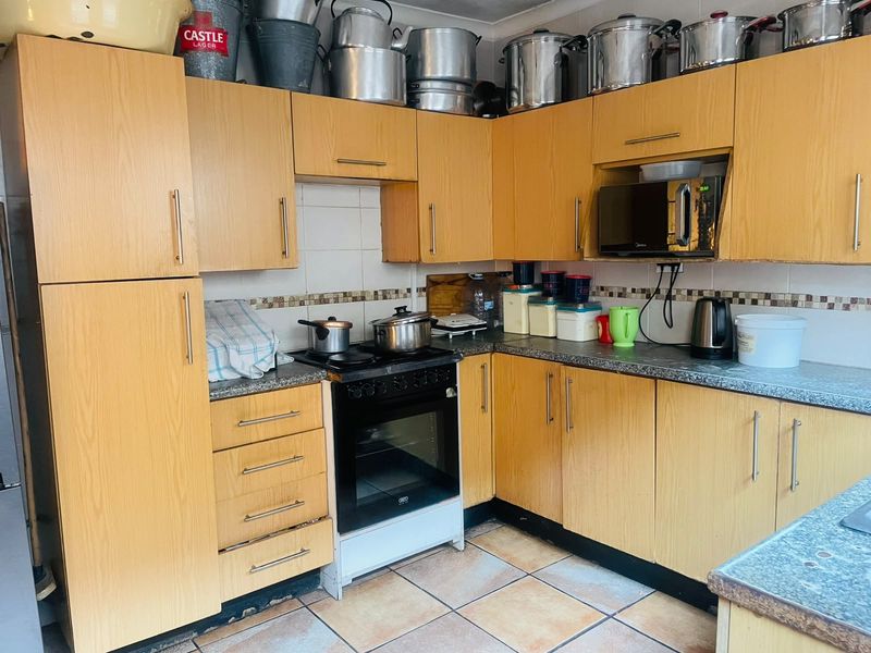 A functional kitchen featuring laminate cabinetry, granite countertops, and a freestanding oven, with tiled flooring and backsplash throughout.
