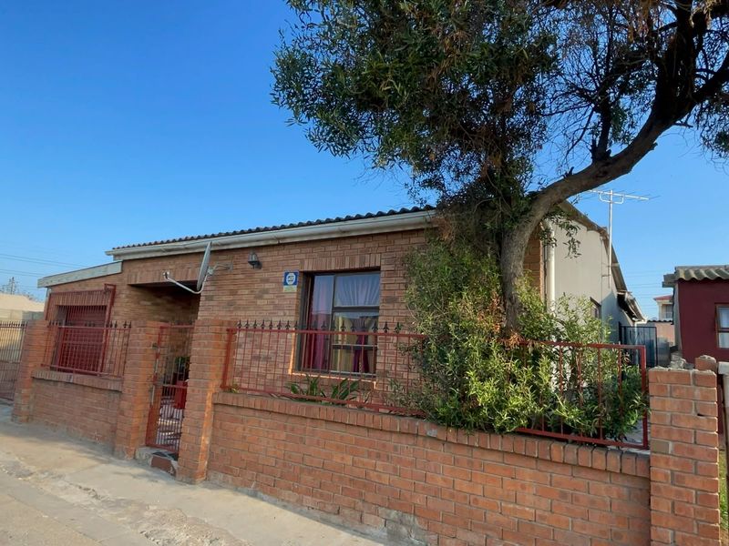 Front elevation of a single-story face brick house featuring metal security fencing and a tiled roof in a residential street setting.