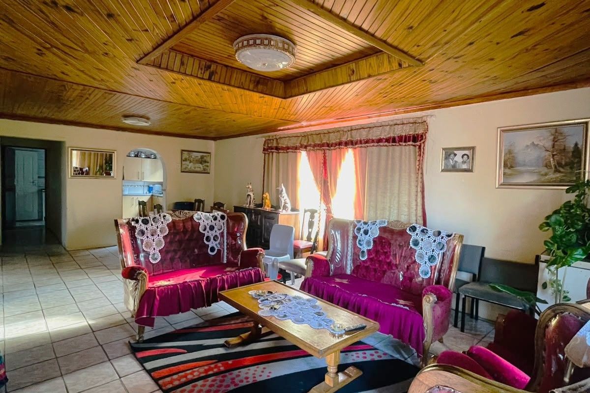 Spacious living room featuring a distinctive timber tongue and groove ceiling with a recessed central feature and neutral ceramic floor tiling.