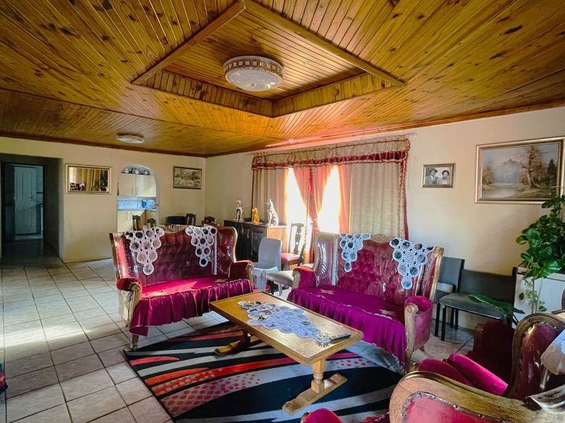 Spacious living room featuring a distinctive timber tongue and groove ceiling with a recessed central feature and neutral ceramic floor tiling.